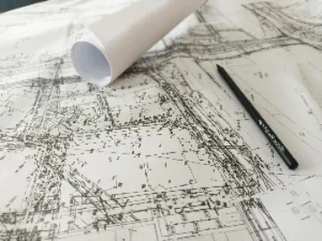 Fragment biało-czarnej mapy geodezyjnej miasta.  Na mapie leży ołówek. 